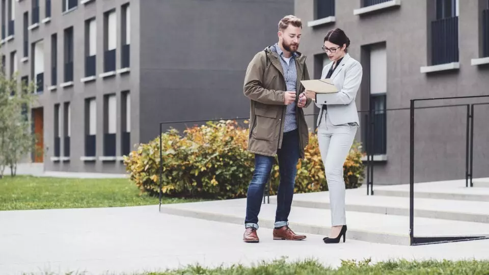 Two people standing while reviewing documents together outside