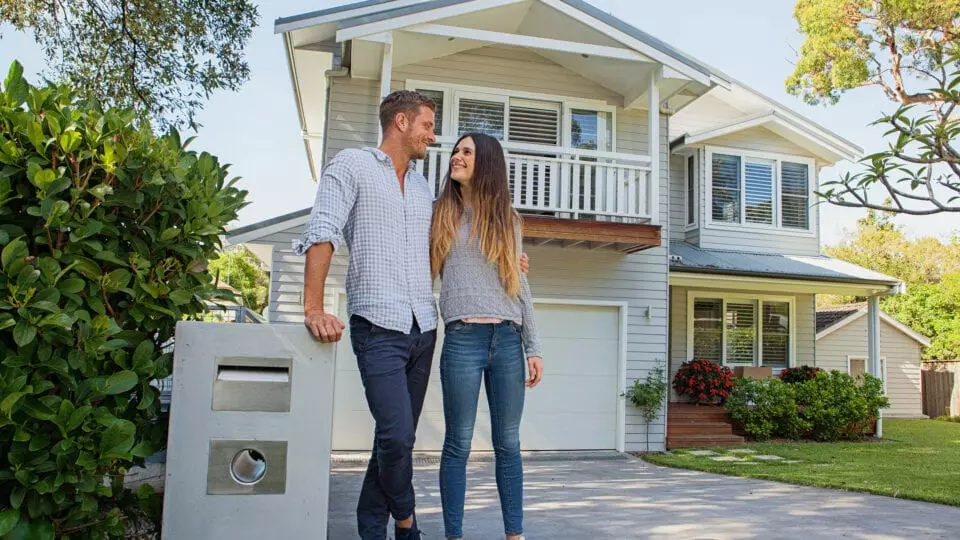 Happy couple standing outside of a house