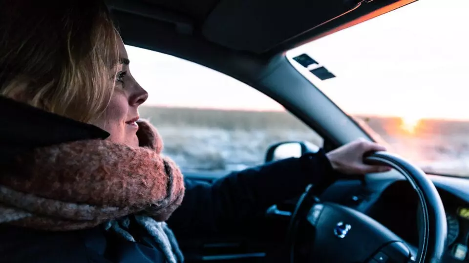 Woman driving in a car at sunset