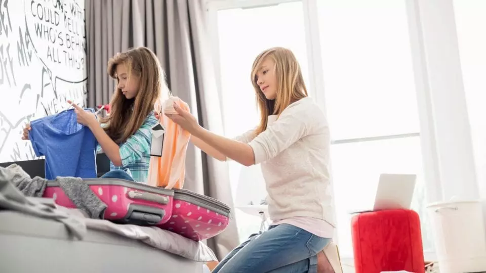 Two girls packing cloths at home
