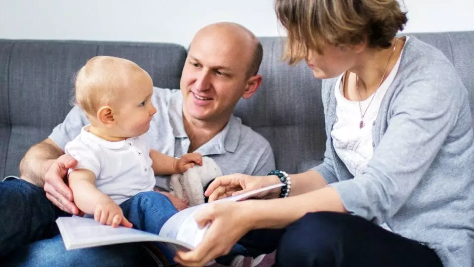 young couple with their new baby on a sofa