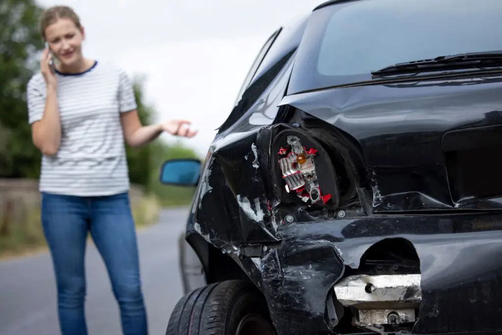 Female standing beside her car after a collision.