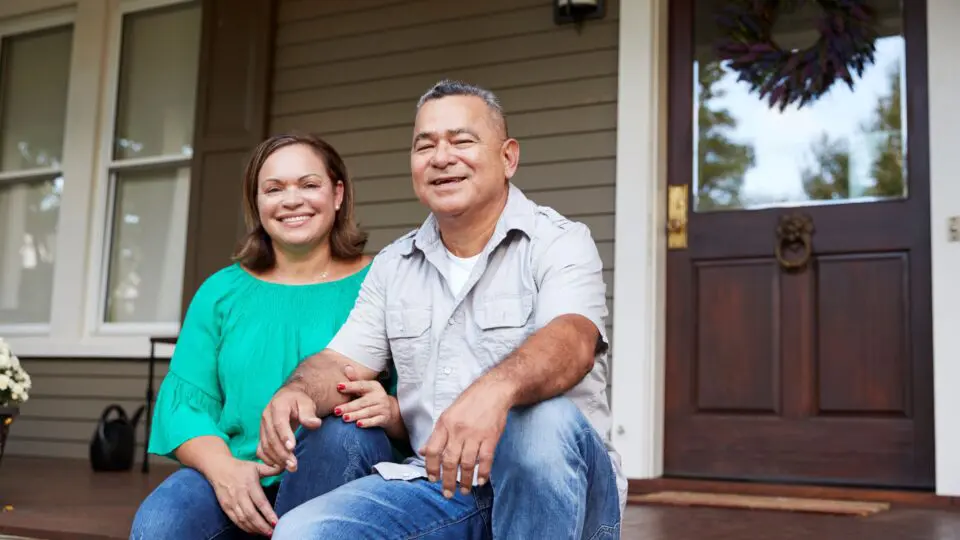 Couple sitting on the front porch of their home.