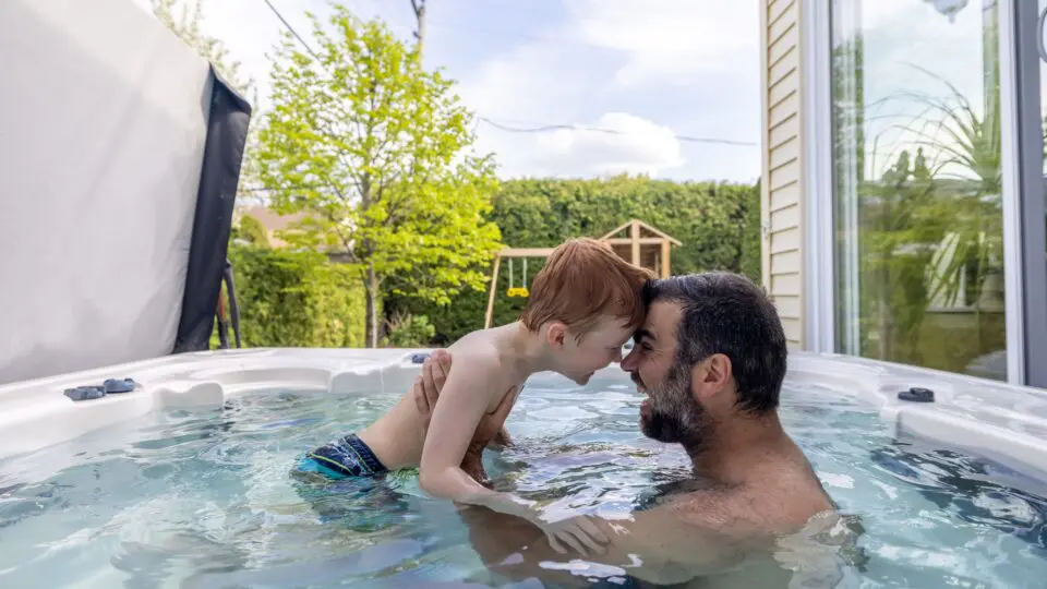 A father and his son enjoying their backyard hot tub.