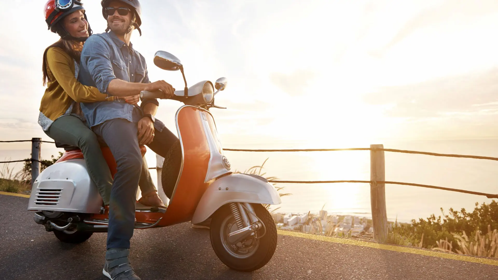 a couple riding on a vespa