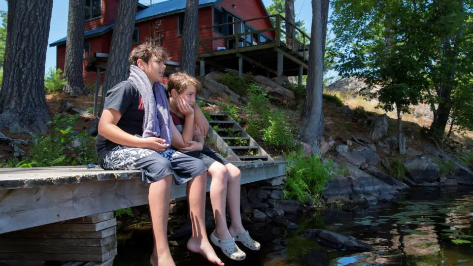 two boys sitting on a cottage deck