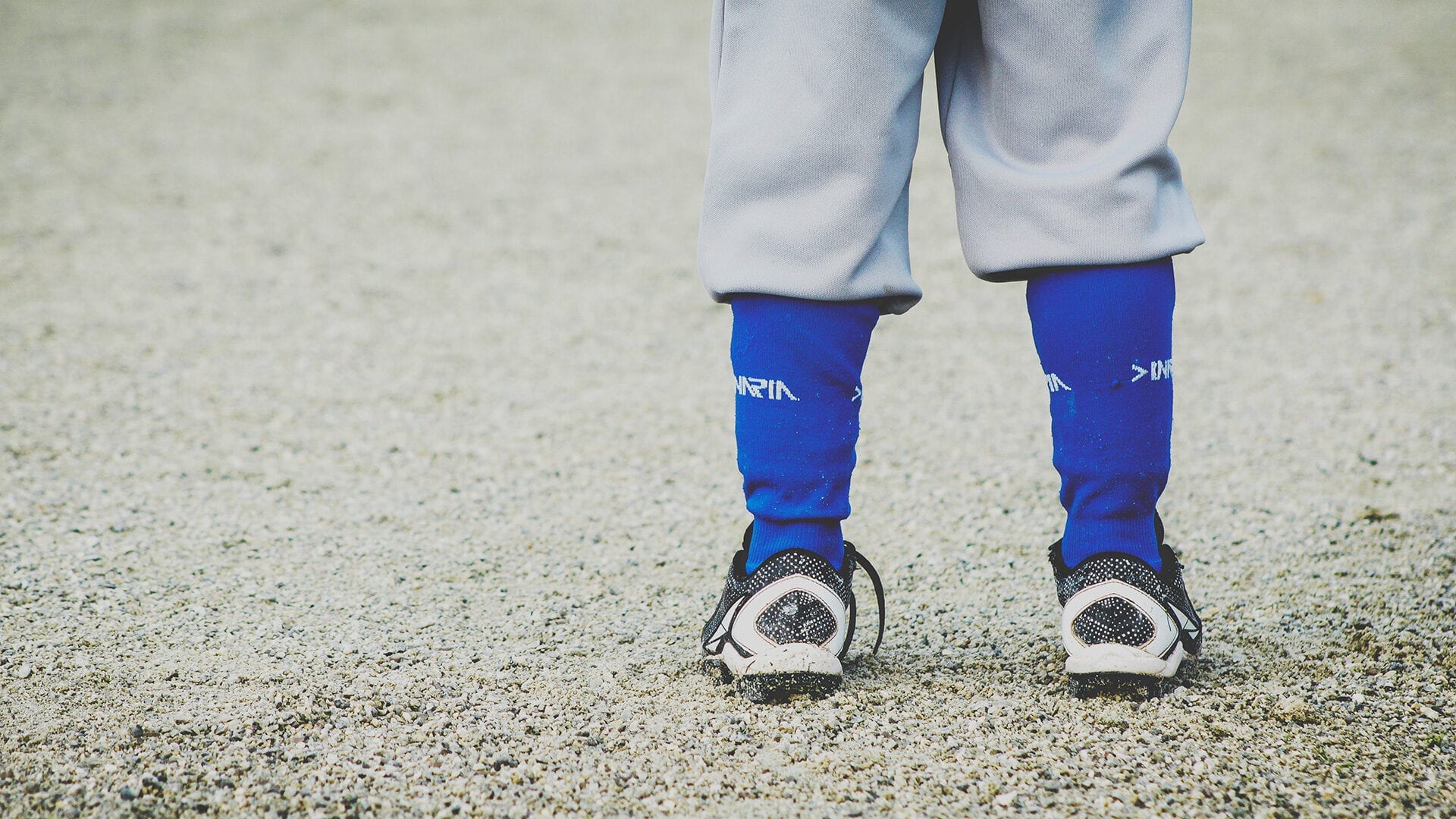 A child's ankles dressed in sports socks and cleats