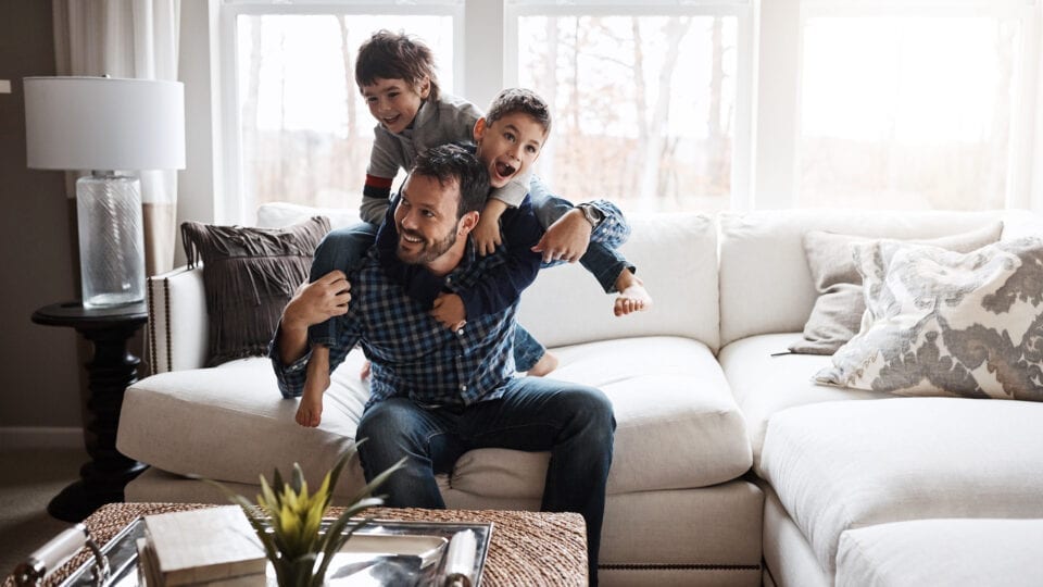 Father with two boys playing on a couch