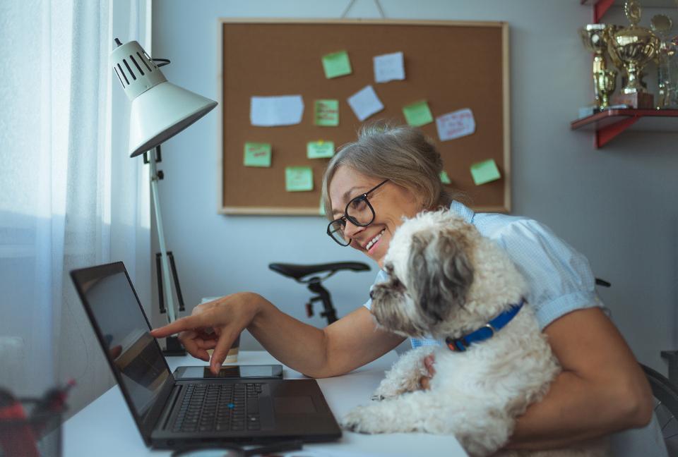 person working on her laptop with her dog on her lap