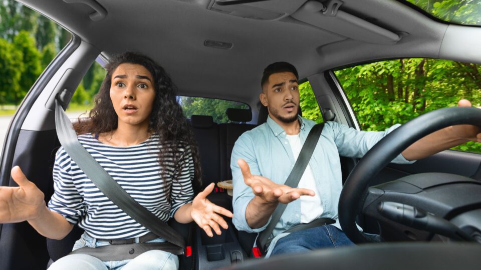 Man and woman confused driving a car.