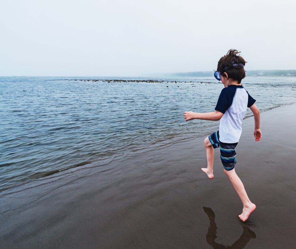 a young person running into the ocean