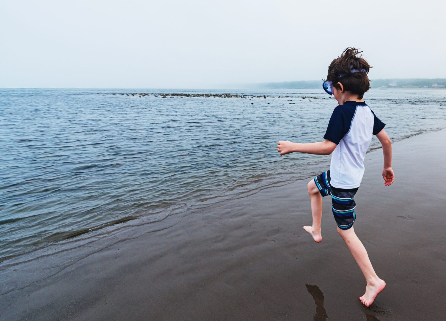 a young person running into the ocean