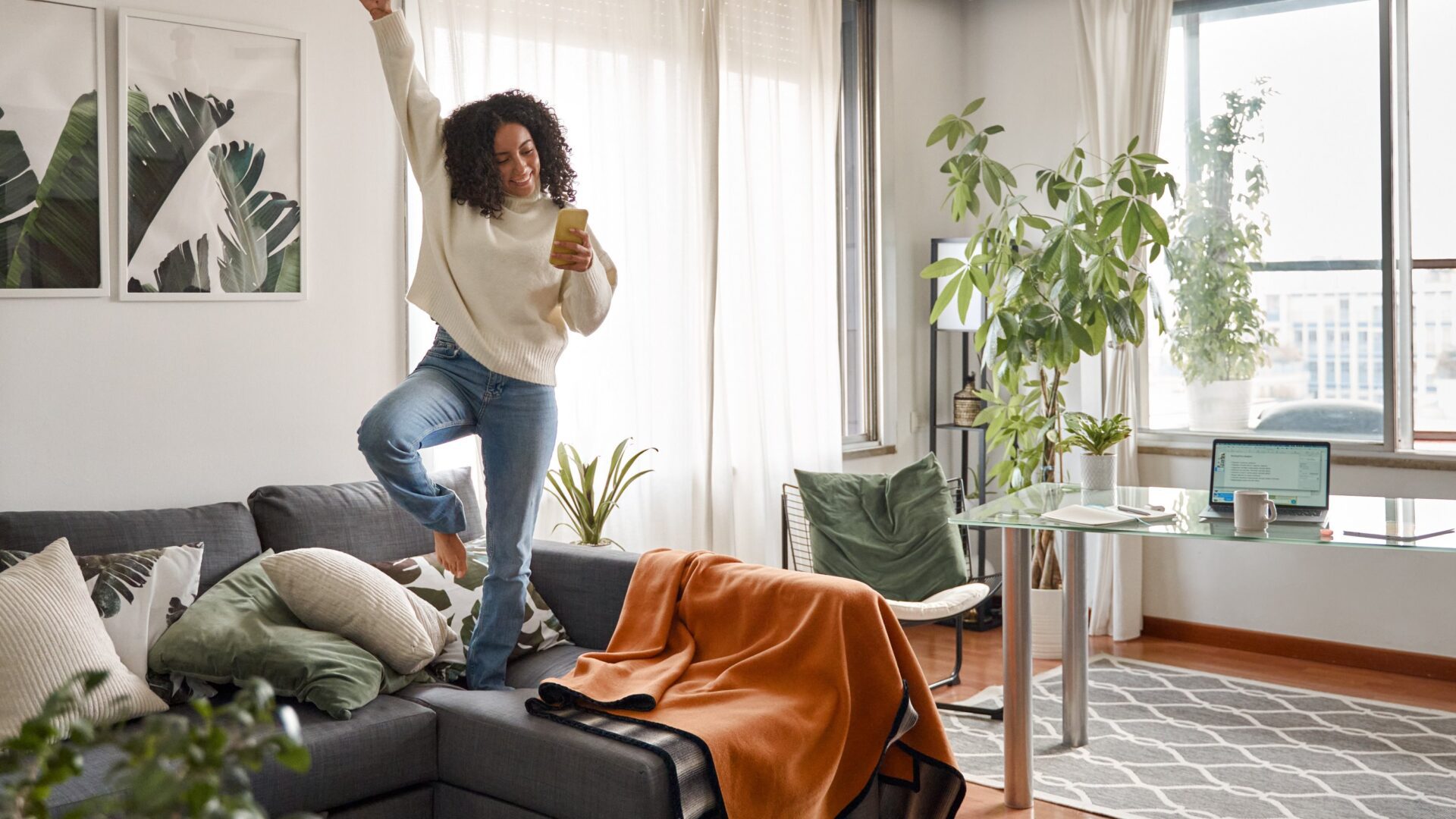 Female jumping on her sofa in her apartment.