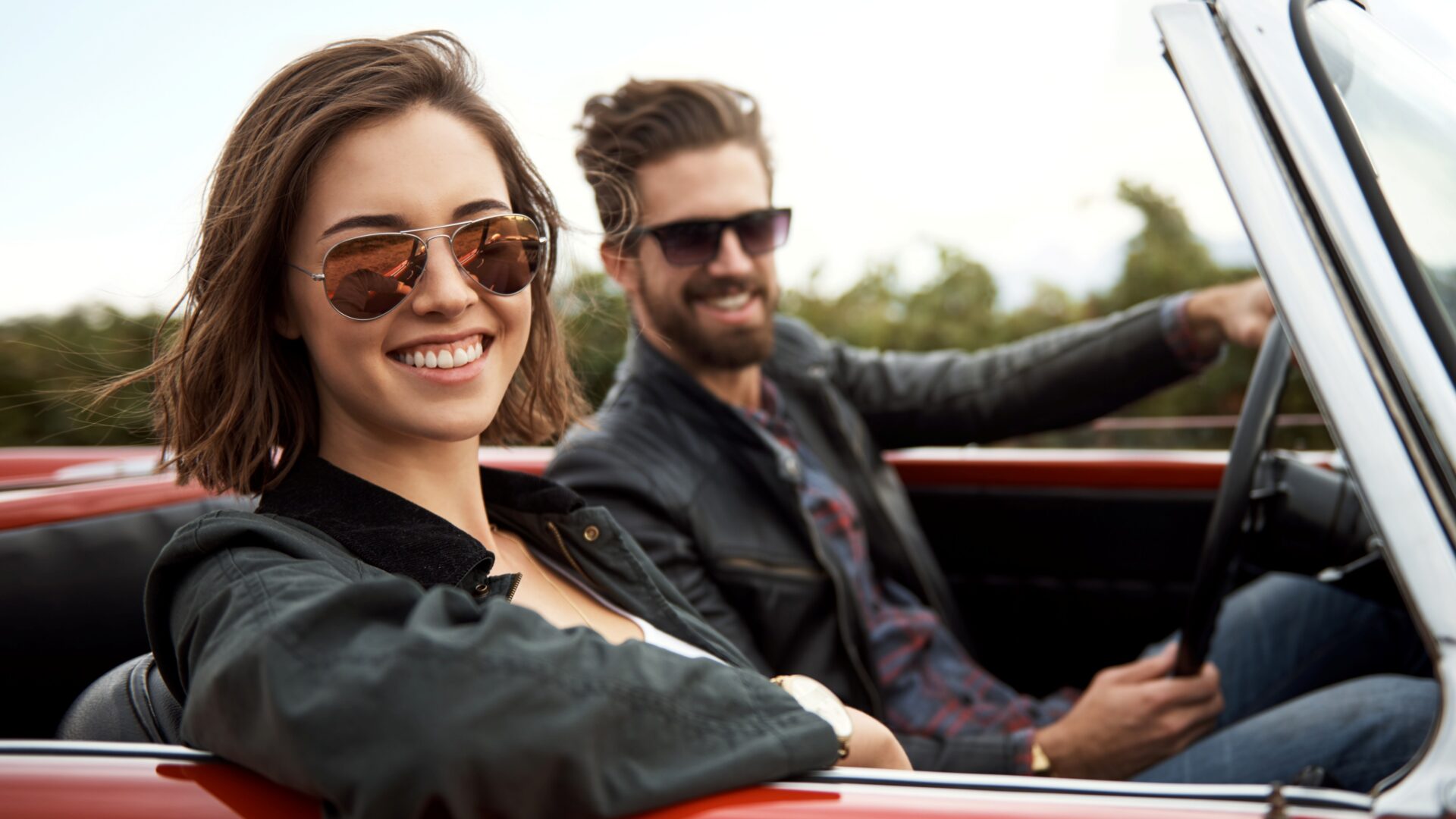 A happy couple driving in a convertable