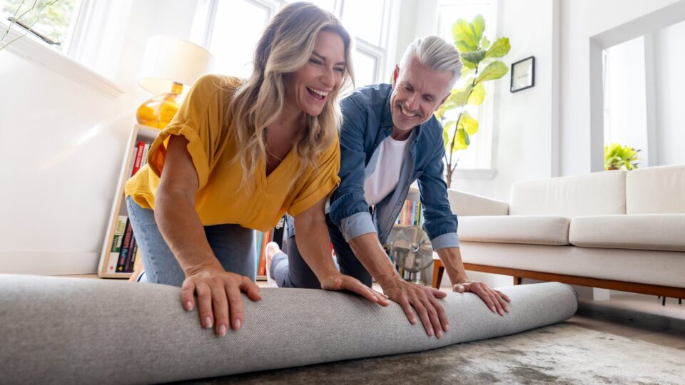 A woman and a man rolling out a carpet