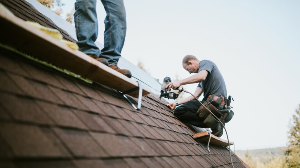 Workers installing new shingles on a roof