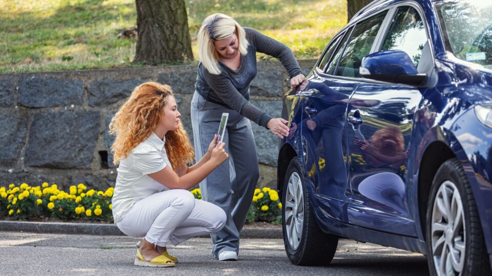 Two women inspecting a car damage